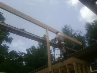Carpenter setting a ridge beam over a new addition frame — Ice Dam Removal by Roofing Brothers in New Marshfield