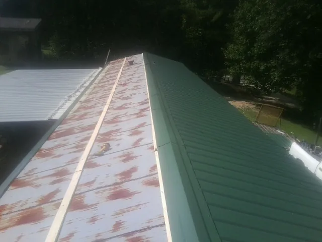 Old rusted panels beside newly installed green metal roofing — Wind Damage Roof Repair by Roofing Brothers in New Marshfield