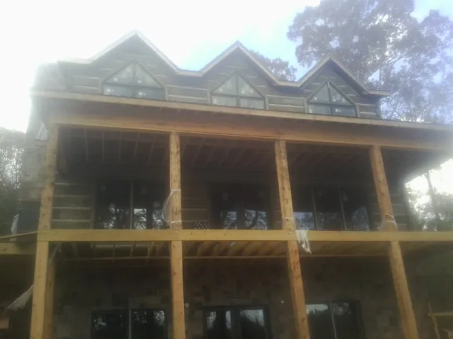 Dormers and porch framing on a large log home under construction — Roof Coating work by our crew in New Marshfield