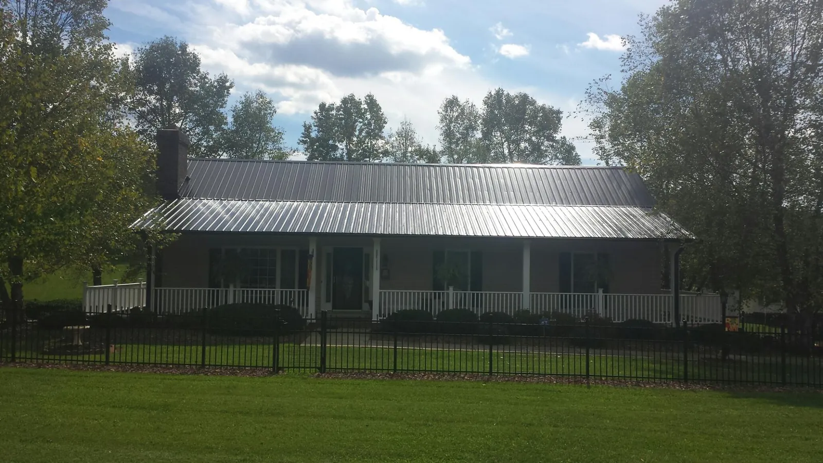 Gray metal roof on a brick ranch with a full width front porch — Gutter Guard Installation work by our crew in New Marshfield