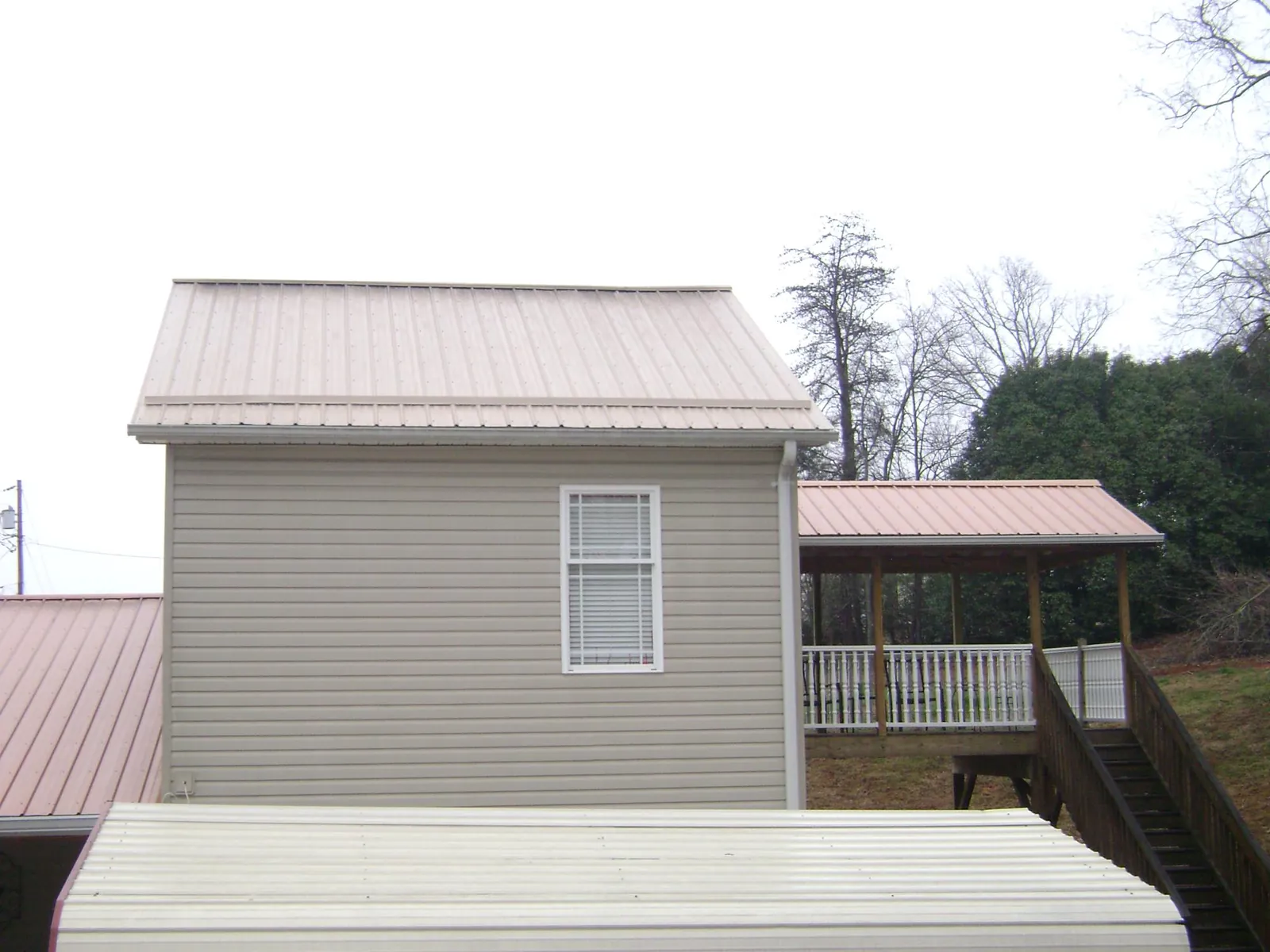 Tan metal roofs on a two story addition and attached porch, from a Roof Replacement job in New Marshfield