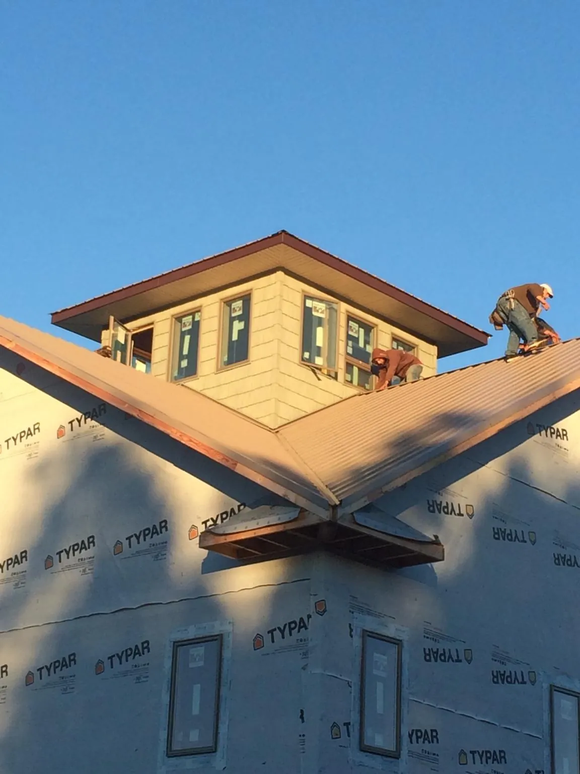 Roofers working around a rooftop cupola on a new metal roof at sunset — Roof Waterproofing in New Marshfield by Roofing Brothers